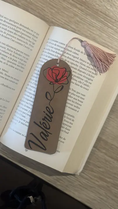 Marque-page en cuir au prénom Valérie avec une rose, réalisé à la Cricut, posé sur un livre ouvert
